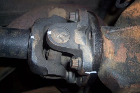 1995 Ford Bronco - Close-up view of a vehicle's driveshaft U-joint, showing wear and rust, with a website logo in the corner.