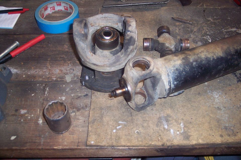 driveshaft, universal joints, and a socket wrench on a workbench