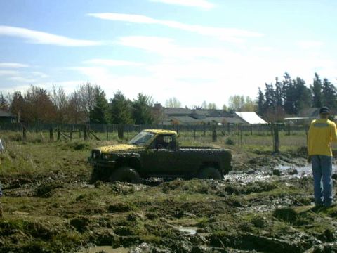 1995 Ford Bronco - A yellow pickup truck is stuck in a muddy field with a person watching.