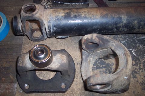 1995 Ford Bronco - Close-up of disassembled driveshaft components, including a yoke and a bearing, on a wooden surface.