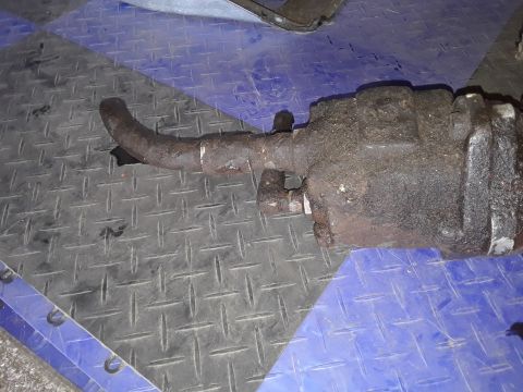1994 Ford Bronco - This rusty power steering gearbox, likely from a Ford Bronco, is shown with a curved hose attached.
