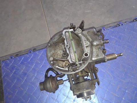 1994 Ford Bronco - A close-up view of a carburetor, likely removed from an older vehicle for repair or replacement.
