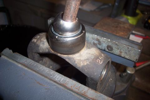 1995 Ford Bronco - Close-up of a driveshaft universal joint secured in a vise, with visible part markings.