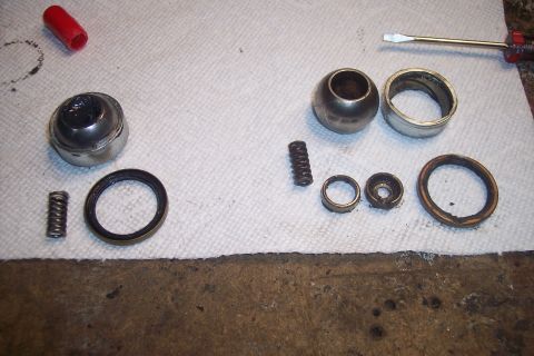 1995 Ford Bronco - Various driveshaft components are disassembled and laid out on a paper towel, alongside a screwdriver and a red cap.