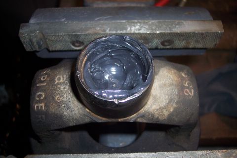1995 Ford Bronco - Close-up of a universal joint part filled with grease, held in a vise. Markings 'SPICE' and '256' are visible.