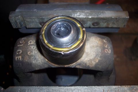 1995 Ford Bronco - Driveshaft U-joint being serviced in a vise, showing lubrication and visible part markings.
