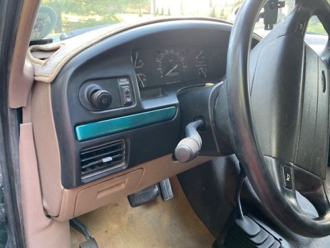 1996 Ford Bronco - The interior of a 1996 Ford Bronco features a tan dashboard with a teal accent strip and a functional instrument cluster.