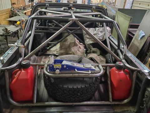 1978 Ford Bronco - Custom roll cage fitted into the bed of a 1978 Ford Bronco, equipped with a spare tire, jack, and fuel cans.