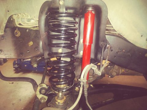 1996 Ford Bronco - Close-up view of vehicle front suspension components, including a coil spring and shock absorber.