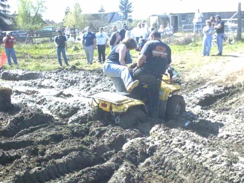 1995 Ford Bronco - An ATV is deeply stuck in a muddy track, with onlookers gathered around.