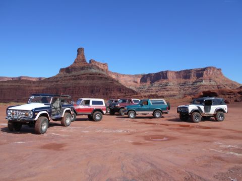 1992 Ford Bronco - Several Ford Broncos are parked in a desert landscape with red rock formations in the background.