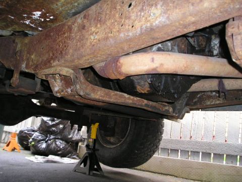 1978 Ford F-250 - The heavily rusted undercarriage of a truck is visible, with the frame and exhaust system showing significant wear.