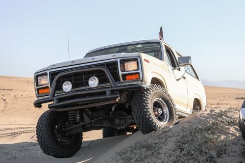 1981 Ford Bronco - This modified Ford Bronco is navigating a sandy incline, with a portion of another vehicle visible in the background.