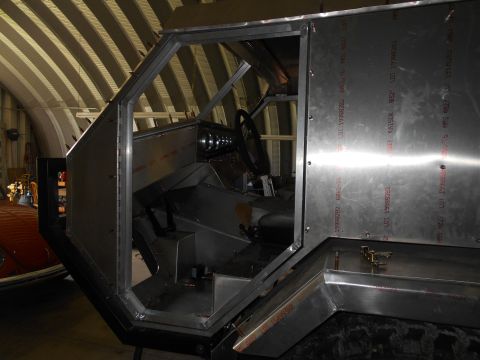 1992 Ford Bronco - The interior of a vehicle under construction shows exposed metal panels and the steering wheel and dashboard area.