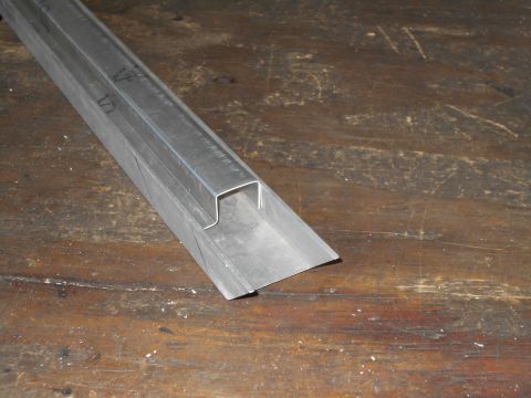 1992 Ford Bronco - A metal channel is shown on a wooden workbench, with visible cut marks and a U-shaped profile.