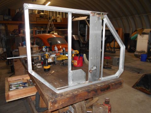 1992 Ford Bronco - A metal frame structure is in the foreground, with an orange Volkswagen Beetle visible behind it in a workshop.