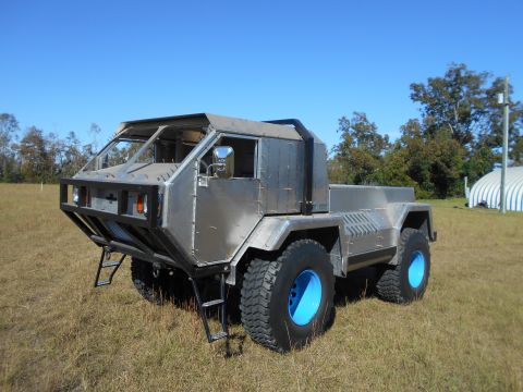 1992 Ford Bronco - This custom-built off-road truck features a unique metal body and large tires with blue rims.