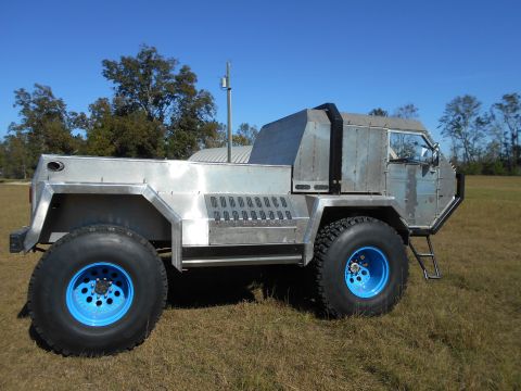1992 Ford Bronco - This custom-built truck features a unique aluminum body and large off-road tires with bright blue wheels.