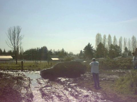 1995 Ford Bronco - A vehicle is deeply mired in a muddy track with a person observing the scene.