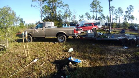 1990 Ford F-250 - A Ford pickup truck is parked in a grassy area, hitched to a trailer, with other vehicles and an RV in the background.