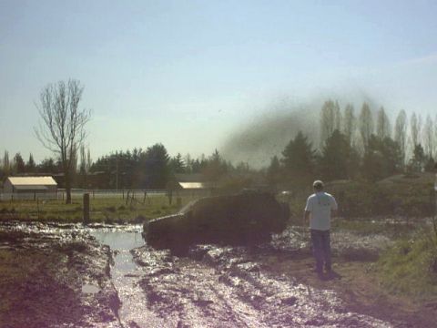 1995 Ford Bronco - A Ford Bronco is stuck in the mud, with a person observing the scene.