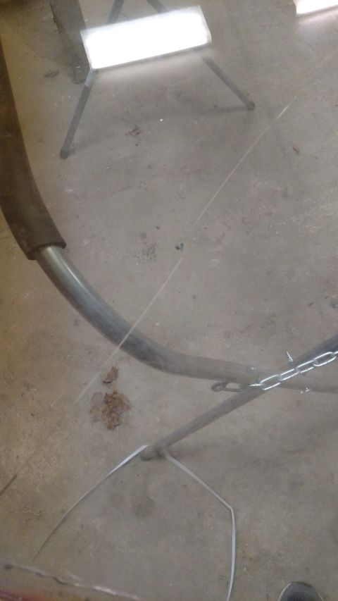 1979 Chevrolet Camaro - Exhaust pipe and chain on concrete floor, with a work light in the background.
