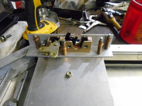 1992 Ford Bronco - A close-up view of a door latch mechanism, likely a replacement part, on a workbench.