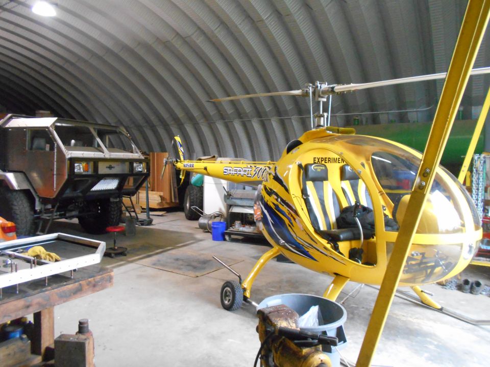 Yellow helicopter and custom truck inside a large garage