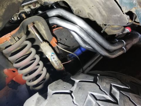 1996 Ford Bronco - Vehicle's undercarriage showing exhaust headers and suspension parts.
