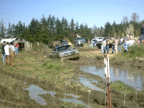 1995 Ford Bronco - A group of people watch as a truck struggles through a muddy obstacle course.