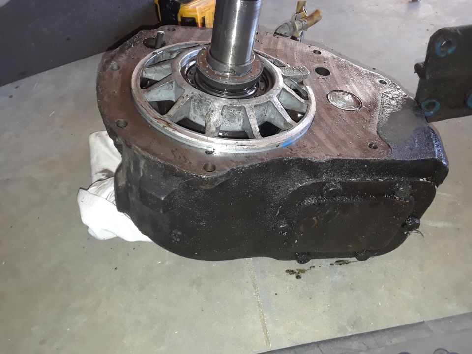 Black automotive transmission housing with a silver metal component and shaft, resting on a white cloth