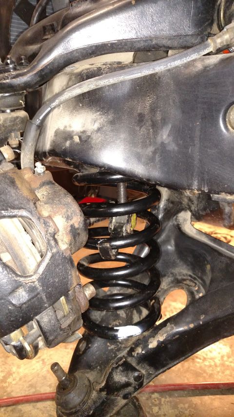 1979 Chevrolet Camaro - Close-up of a car's front suspension system, showing a black coil spring and brake caliper.