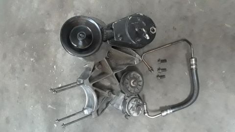 1994 Ford Bronco - A disassembled power steering pump assembly with hoses and mounting hardware.