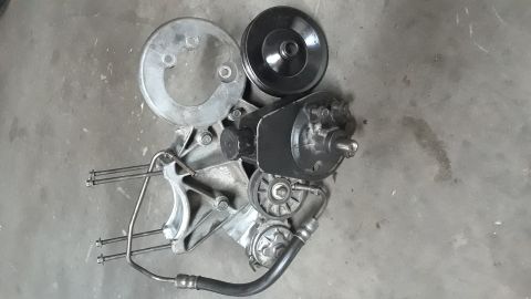 1994 Ford Bronco - A power steering pump assembly, including pulleys and hoses, is shown laid out on a concrete floor.