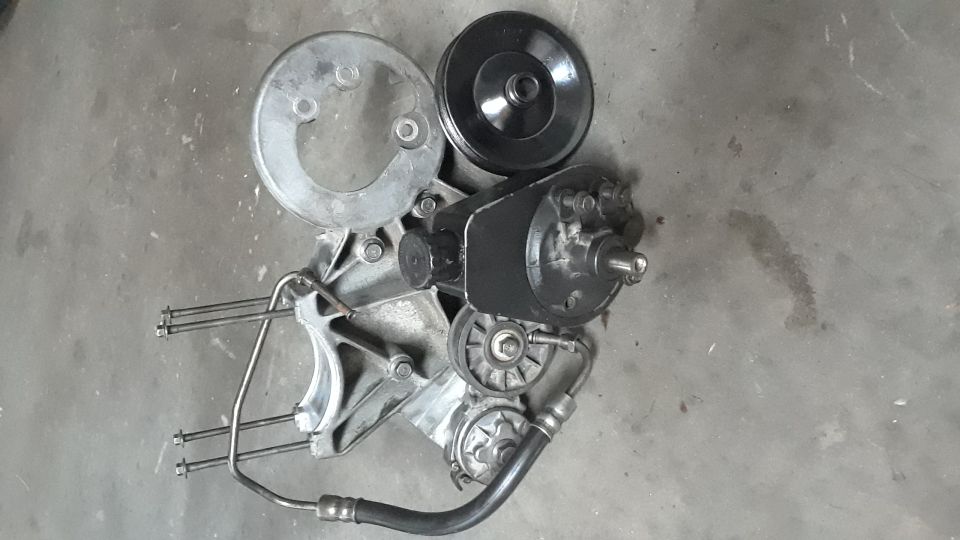 Power steering pump assembly with pulleys and hoses on a concrete surface