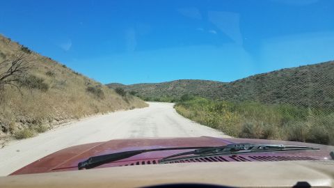 1985 Ford Bronco - Driving down a remote dirt road through arid hills on a sunny day.