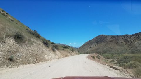 1985 Ford Bronco - Driving on a dusty road through a hilly, arid landscape on a sunny day.