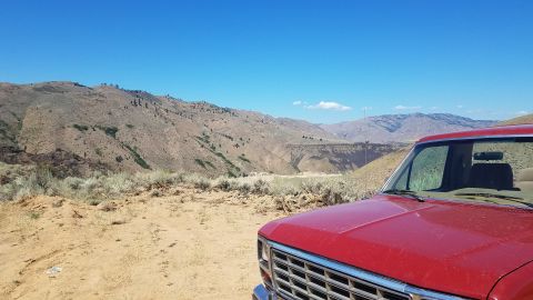 1985 Ford Bronco - Red SUV parked in a desert landscape with mountains in the background.