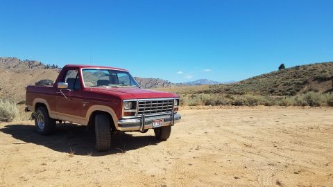 1985 Ford Bronco - Red 1985 Ford Bronco parked in a desert landscape under a clear blue sky.