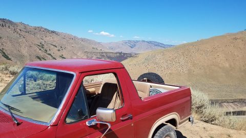 1985 Ford Bronco - Red 1985 Ford Bronco parked in a desert landscape with mountains.