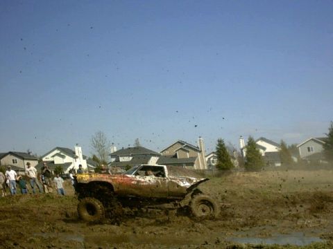 1995 Ford Bronco - Mud bogging event with a heavily modified pickup truck struggling in the mire.