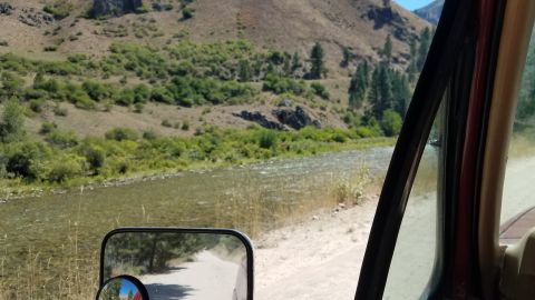 1985 Ford Bronco - Driving through a scenic mountain area with a river alongside the road.