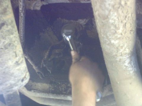 1995 Ford Bronco - Close-up of a hand working on a vehicle's undercarriage with a socket wrench.