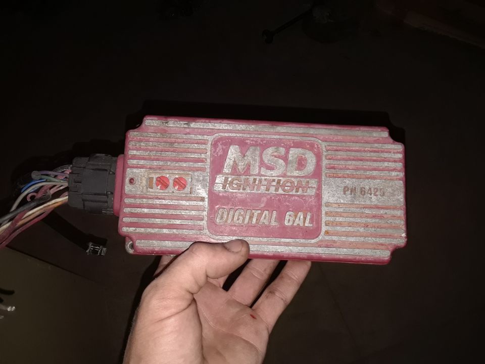 Red MSD Ignition Digital 6AL ignition box with wiring harness, held by a hand