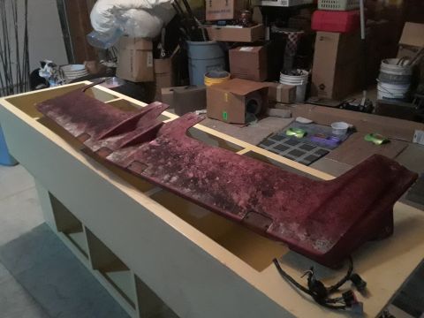 1994 Ford Bronco - Unidentified red plastic car part is stored on a workbench in a cluttered garage.