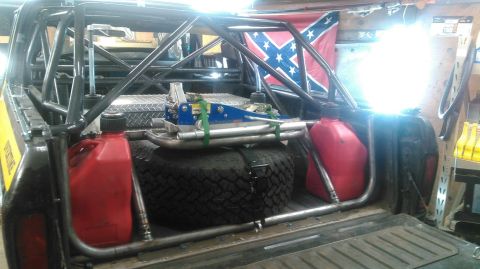 1978 Ford Bronco - Interior view of a truck bed modified with a roll cage, spare tire, and fuel cans.