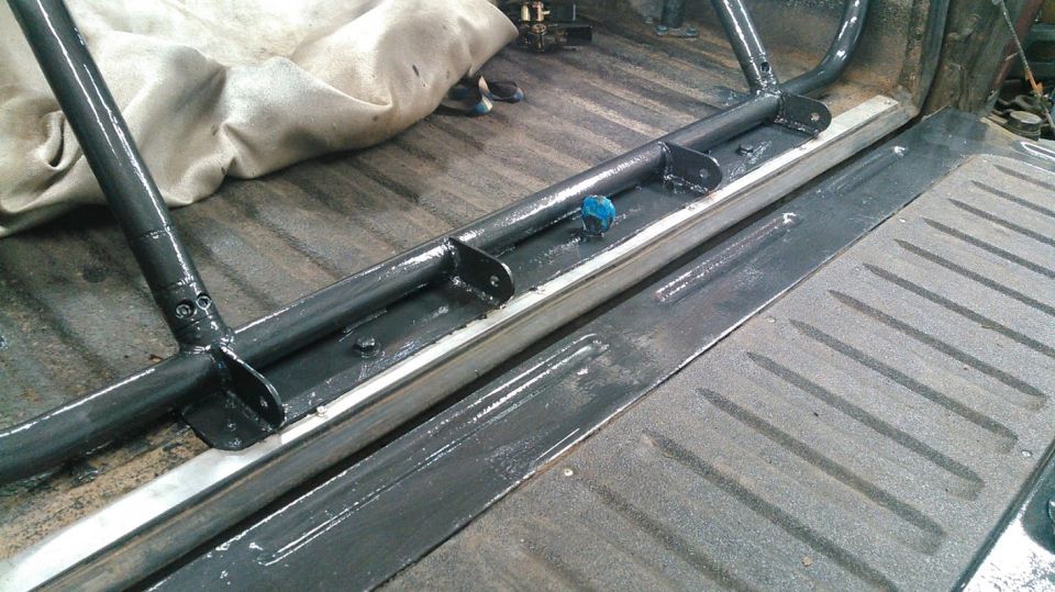 Roll cage installed in truck bed, showing mounting brackets and tubing