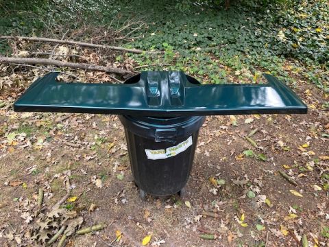 1996 Ford Bronco - A green rear spoiler is placed on a trash can in a wooded area.