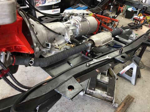 1992 Jeep Wrangler - The vehicle's engine, transmission, and exhaust components are assembled and supported on jack stands in a workshop.