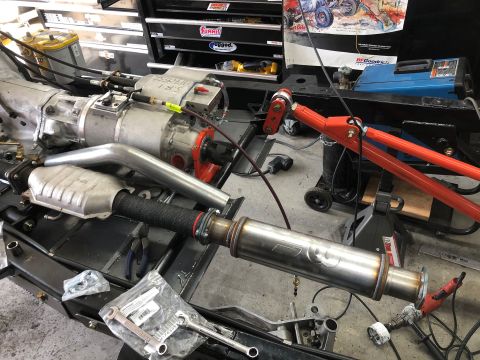 1992 Jeep Wrangler - Close-up view of a vehicle's exhaust system and transmission components in a workshop setting.